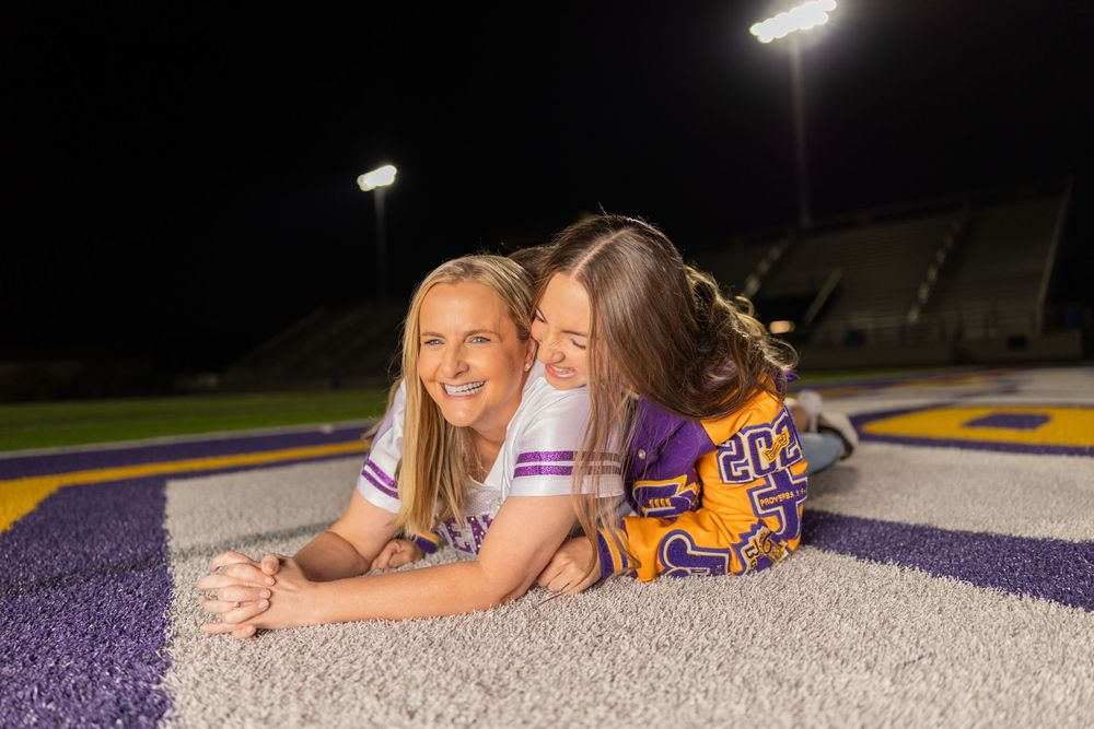 Athletes in school colors share candid moment on football field at night.