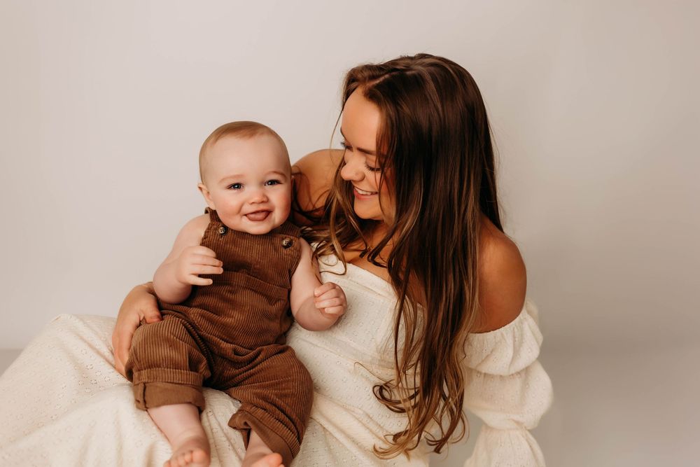 A loving parent shares tender moments with their baby in a series of heartwarming studio portraits against a neutral backdrop.
