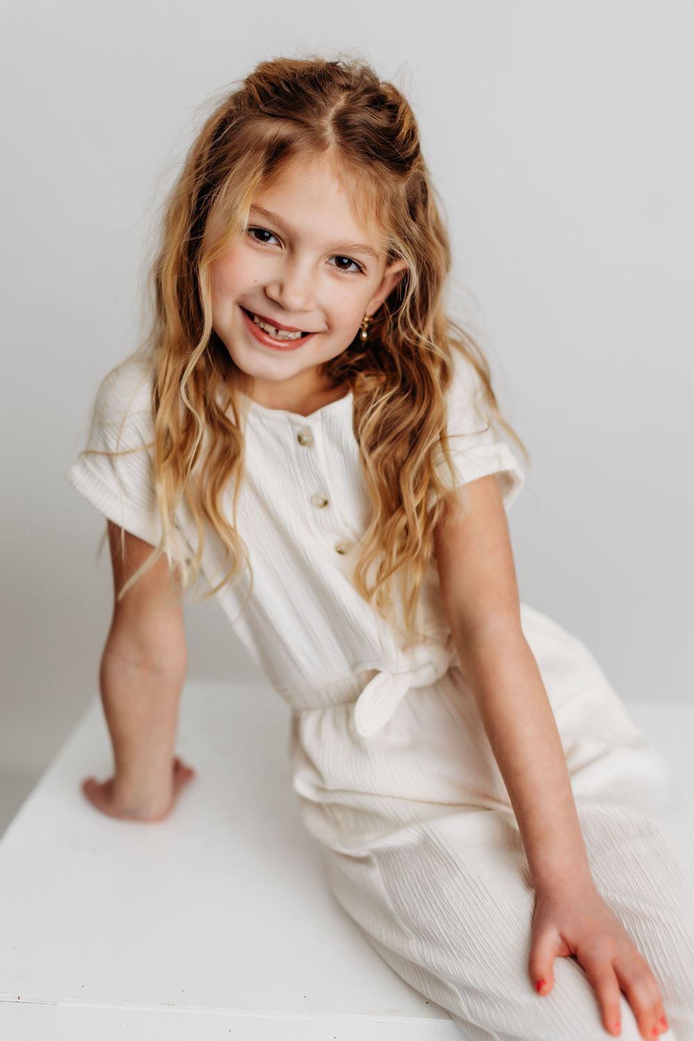 A sequence of playful poses in white clothing against a light gray studio backdrop.