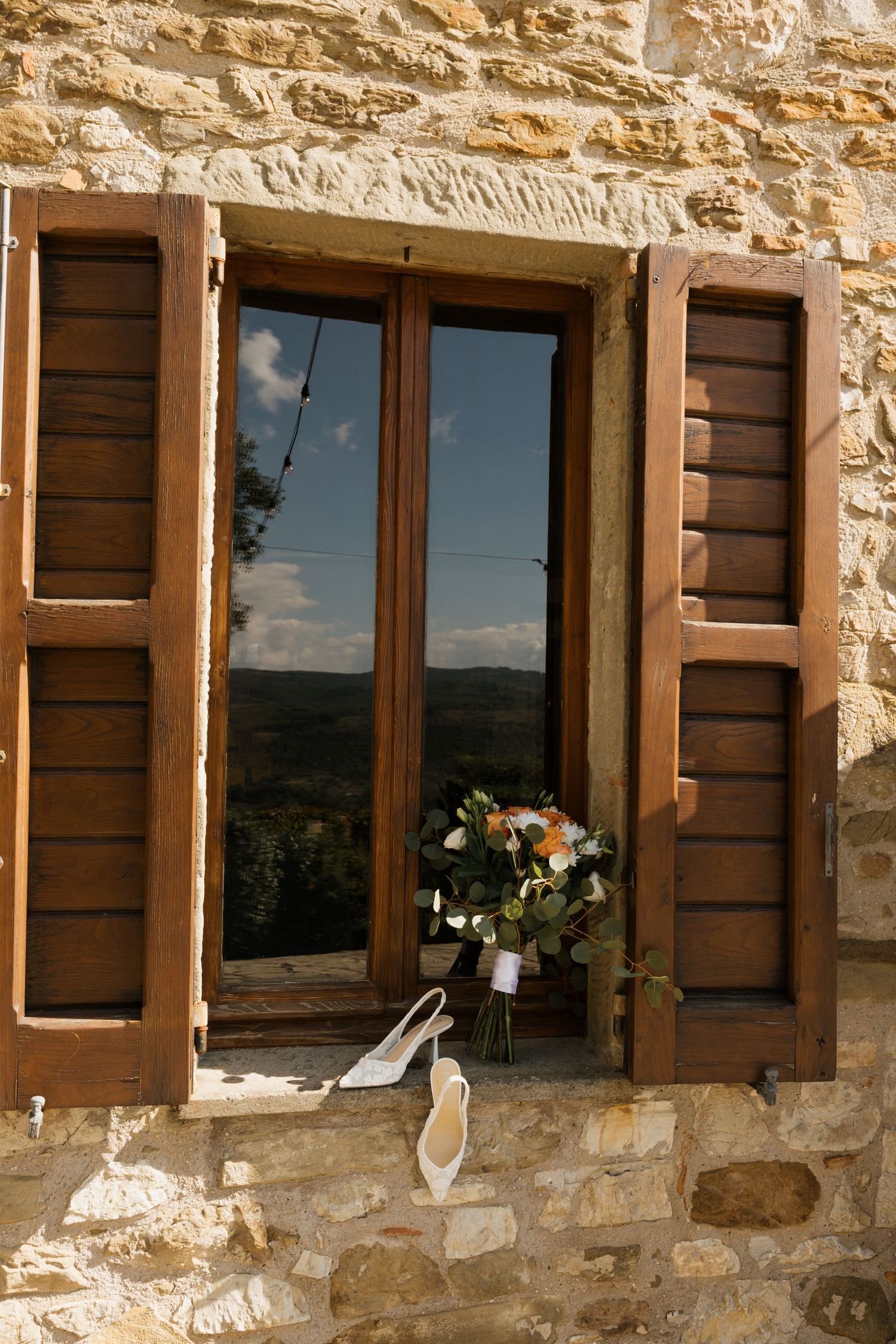 Stone building exterior with wooden shuttered windows in warm evening light.
