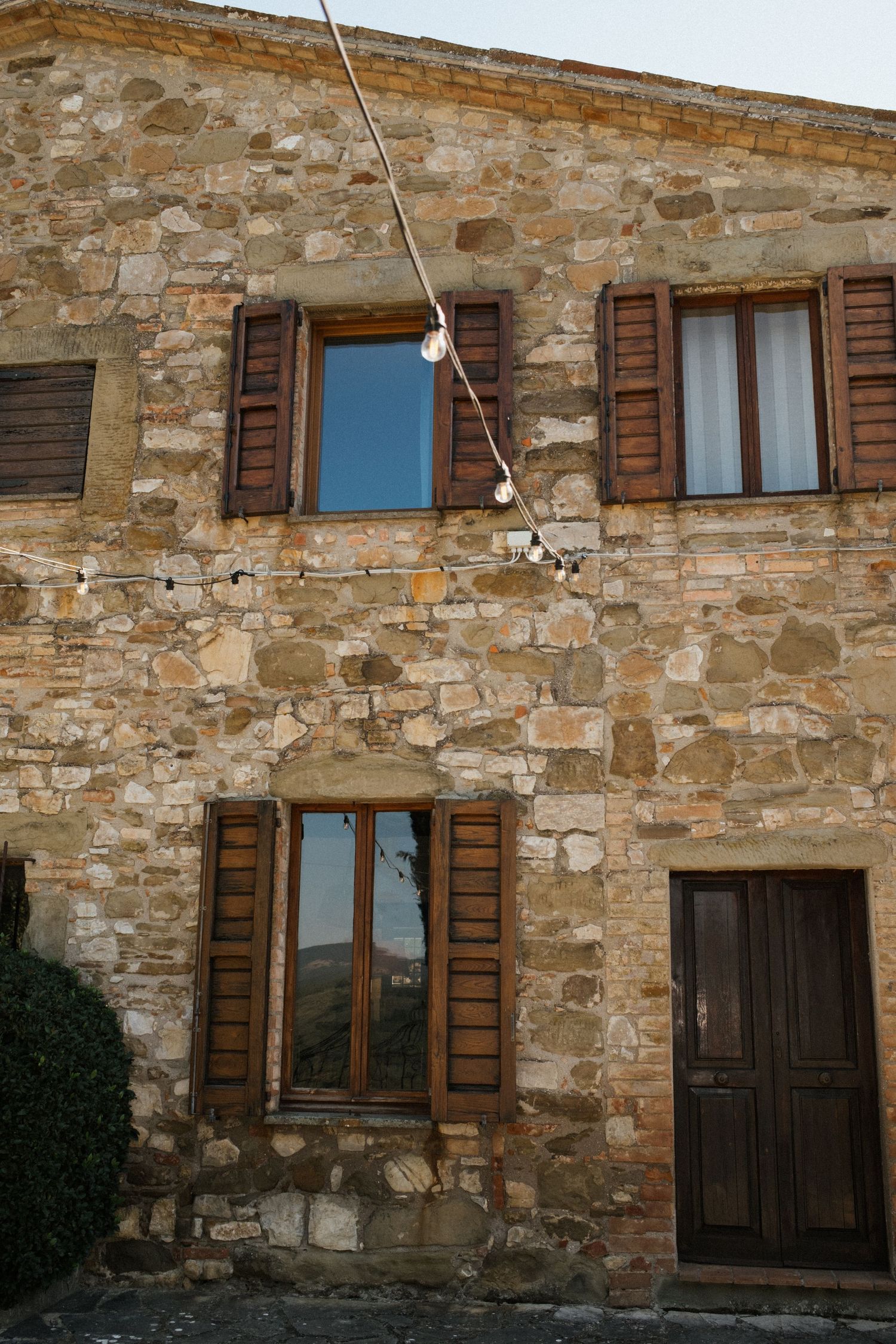 Exterior view of a rustic stone building with wooden shuttered windows.