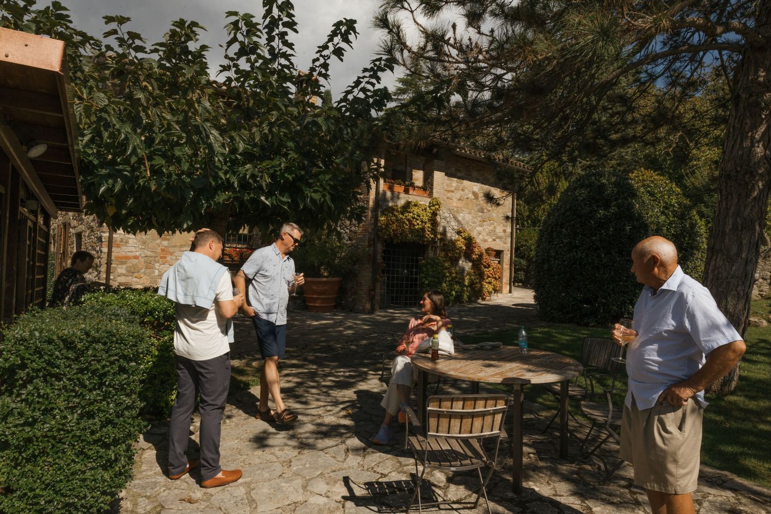 Guests gather in a rustic stone courtyard with outdoor seating during a daytime event.