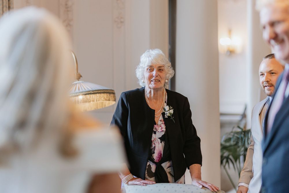 Family members share emotional reactions during a wedding celebration in an elegant indoor venue.