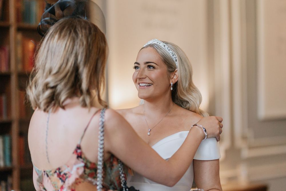 A bride and bridesmaids share emotional hugs and embraces during a wedding celebration.