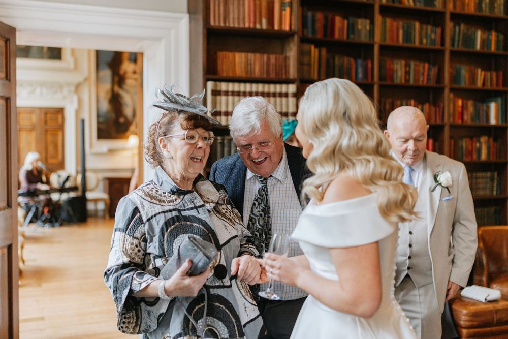 Elderly couples dancing together at a library social event with bookshelves lining the walls.
