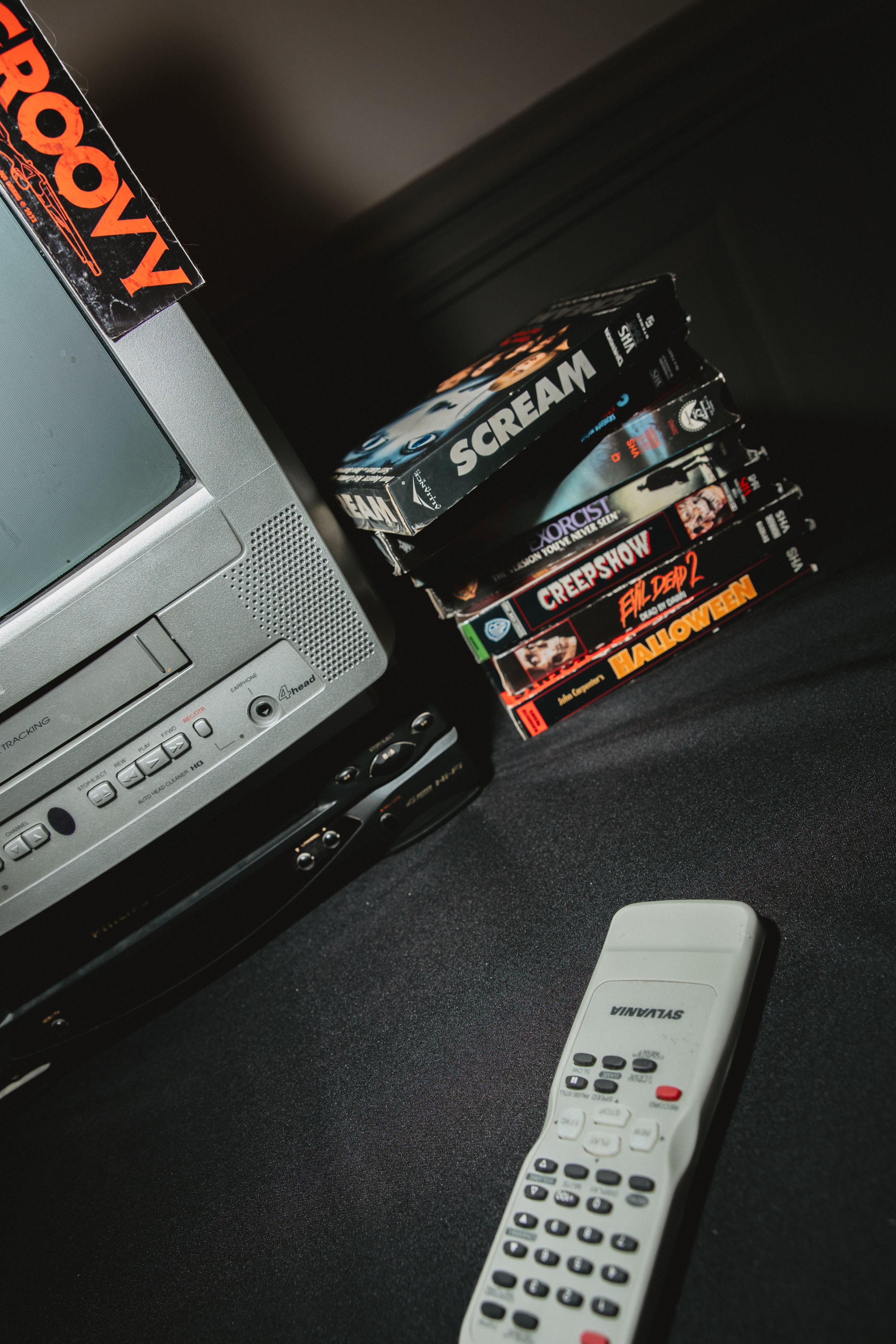 Remote control and vintage video game cartridges arranged on dark surface with dramatic lighting.