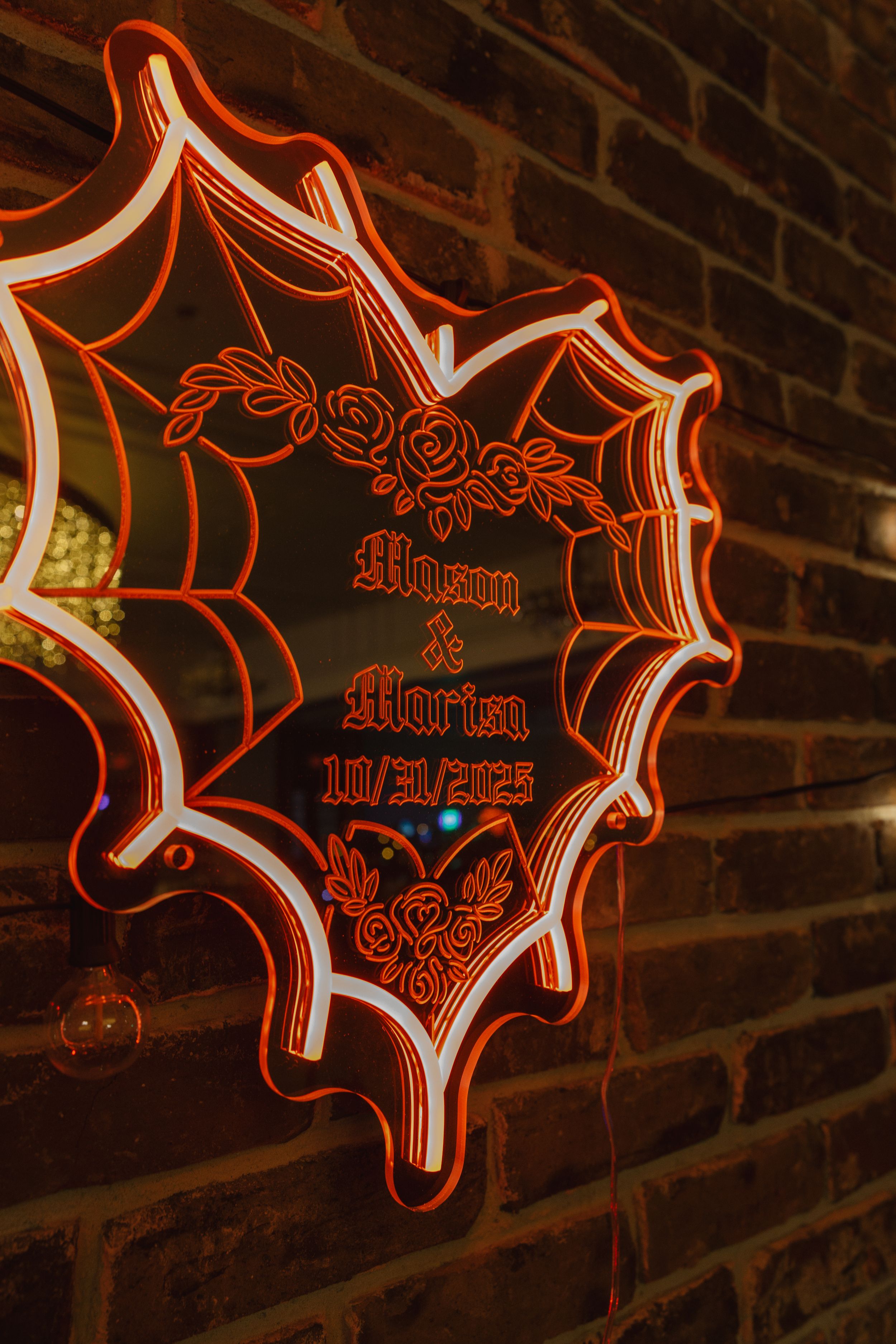 Red neon signs with decorative text designs mounted on a dark brick wall create an atmospheric display.