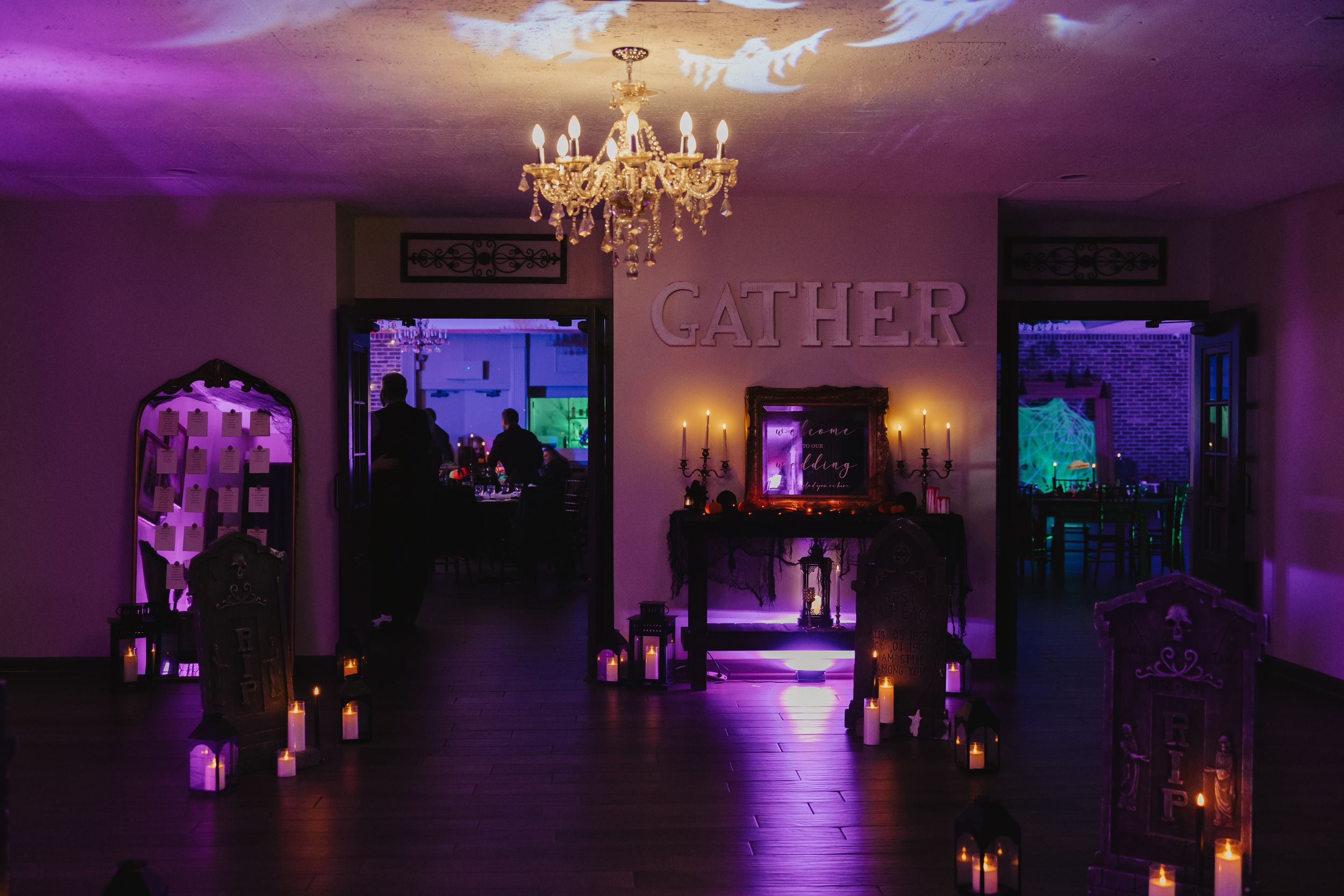Purple and blue mood lighting illuminates an elegant event space with chandeliers and candlelit tables.