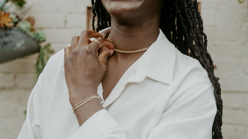 Detail shot of neck and shoulders wearing white collared shirt with delicate necklace.