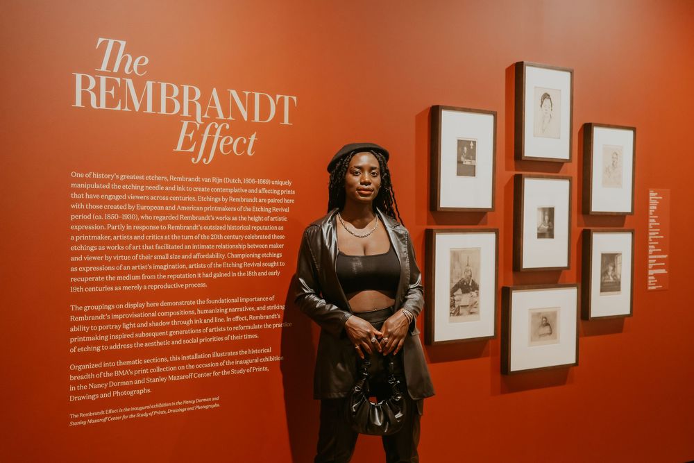 Museum visitor standing in front of The Rembrandt Effect exhibition wall display.