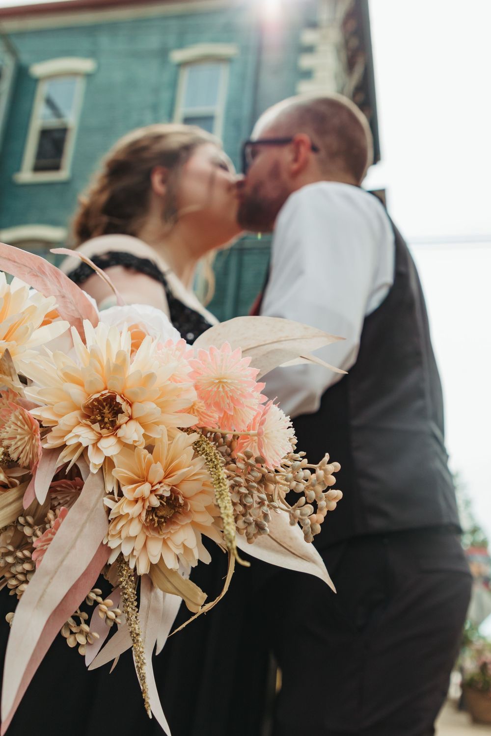 Delicate peach and cream colored floral bouquet with dried flowers and ribbons against a blurred background.