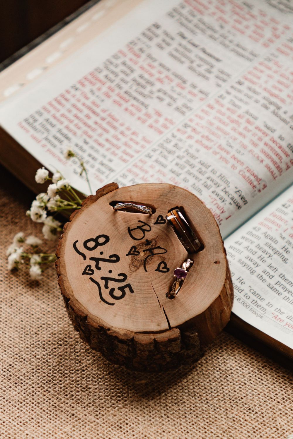 Rustic wooden log slices with handwritten text serve as decorative elements alongside an open book and delicate white flowers.