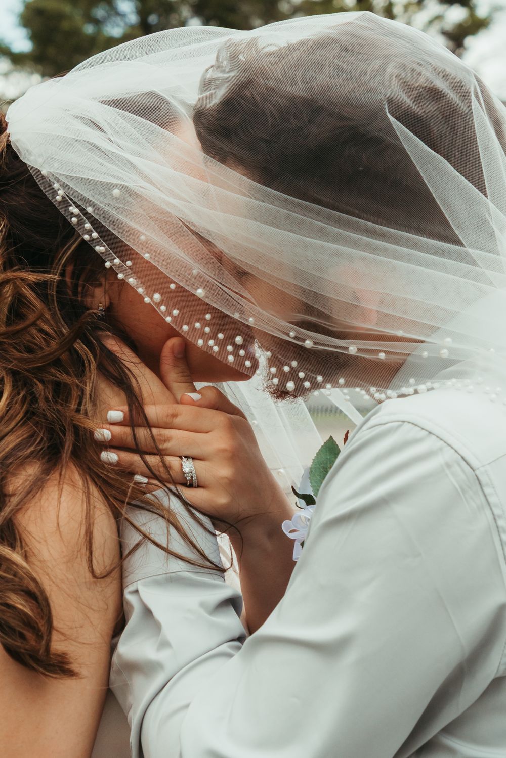 Close-up shots of a bride in a white veil with pearl details during an intimate wedding moment.