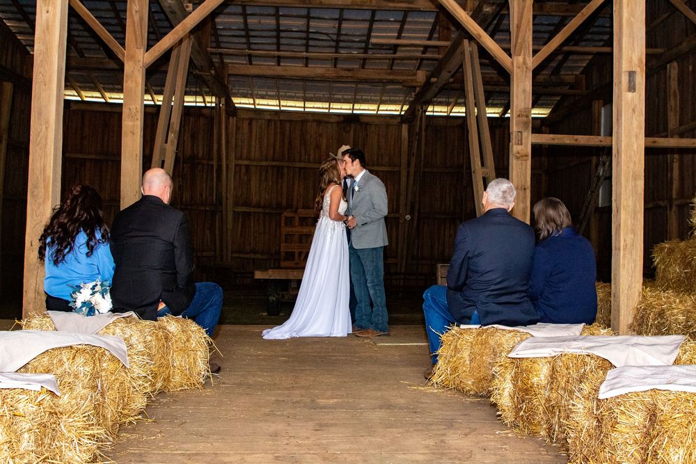 A rustic barn wedding venue interior decorated with hay bales and wooden beams.
