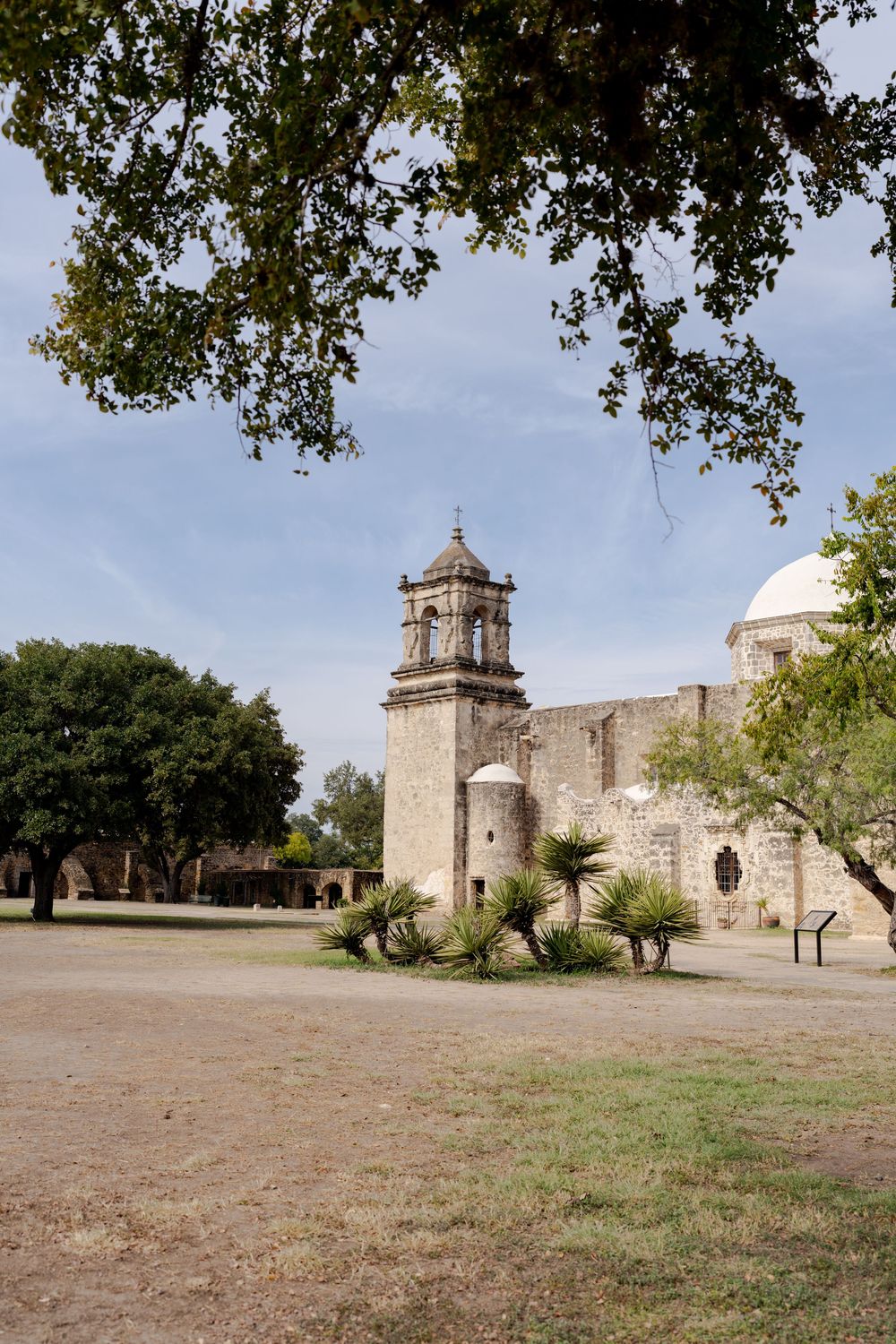 Historic Spanish colonial mission architecture with stone walls and bell towers under blue sky.