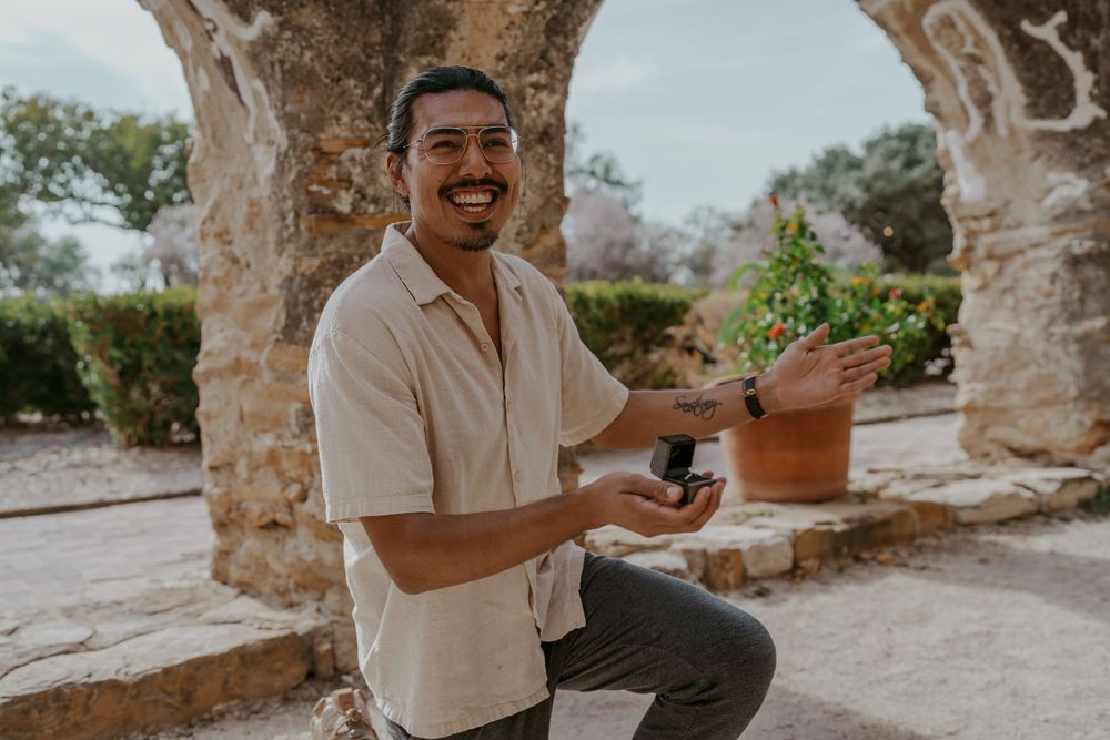 A proposal scene unfolds along the stone walkway of a historic mission.