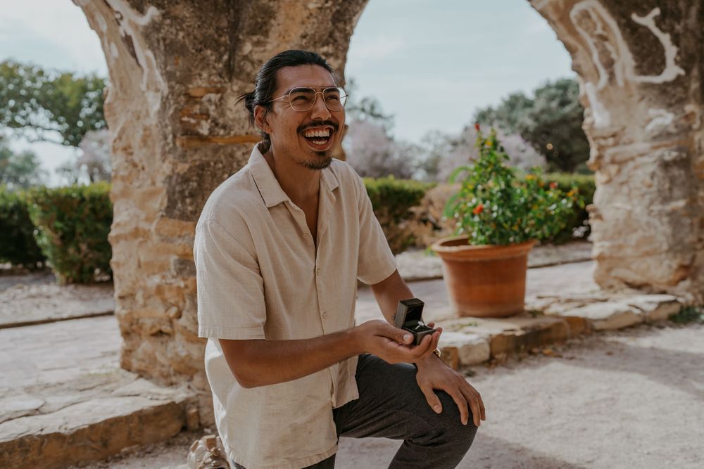 A couple shares a joyful moment in a historic stone courtyard setting.