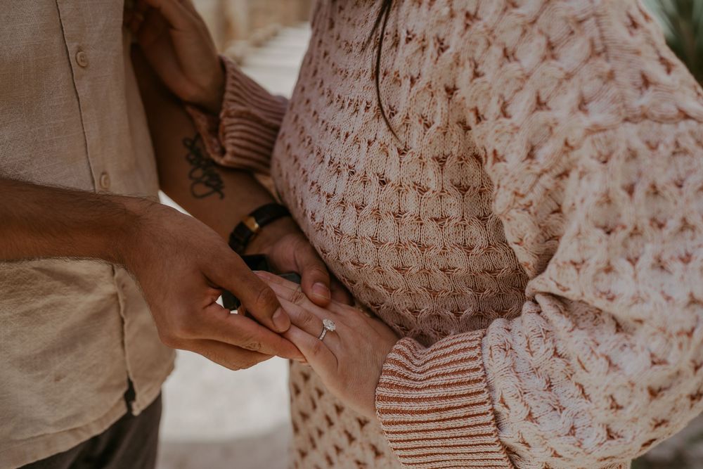 A couple embraces while wearing coordinated neutral-toned outfits.