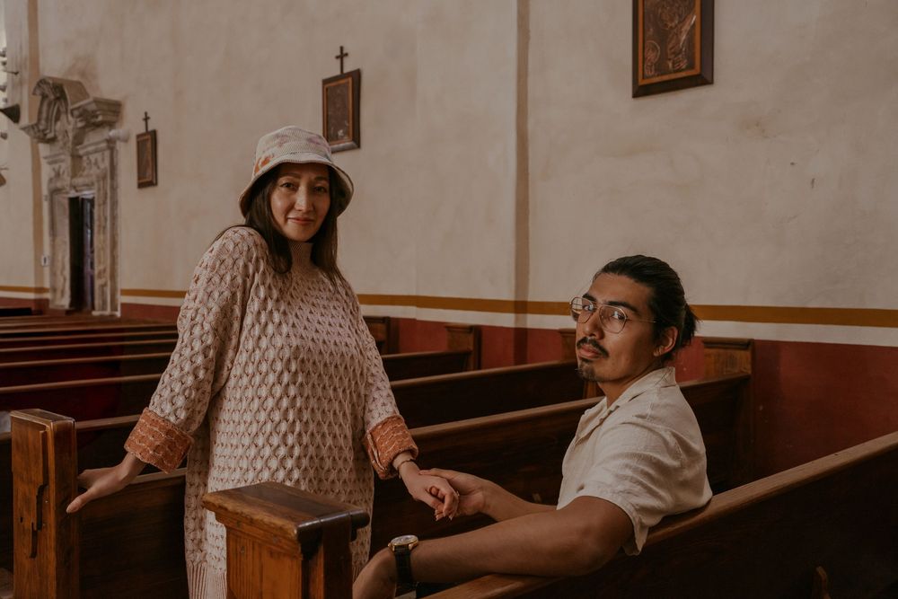 Two people sitting together in wooden church pews.