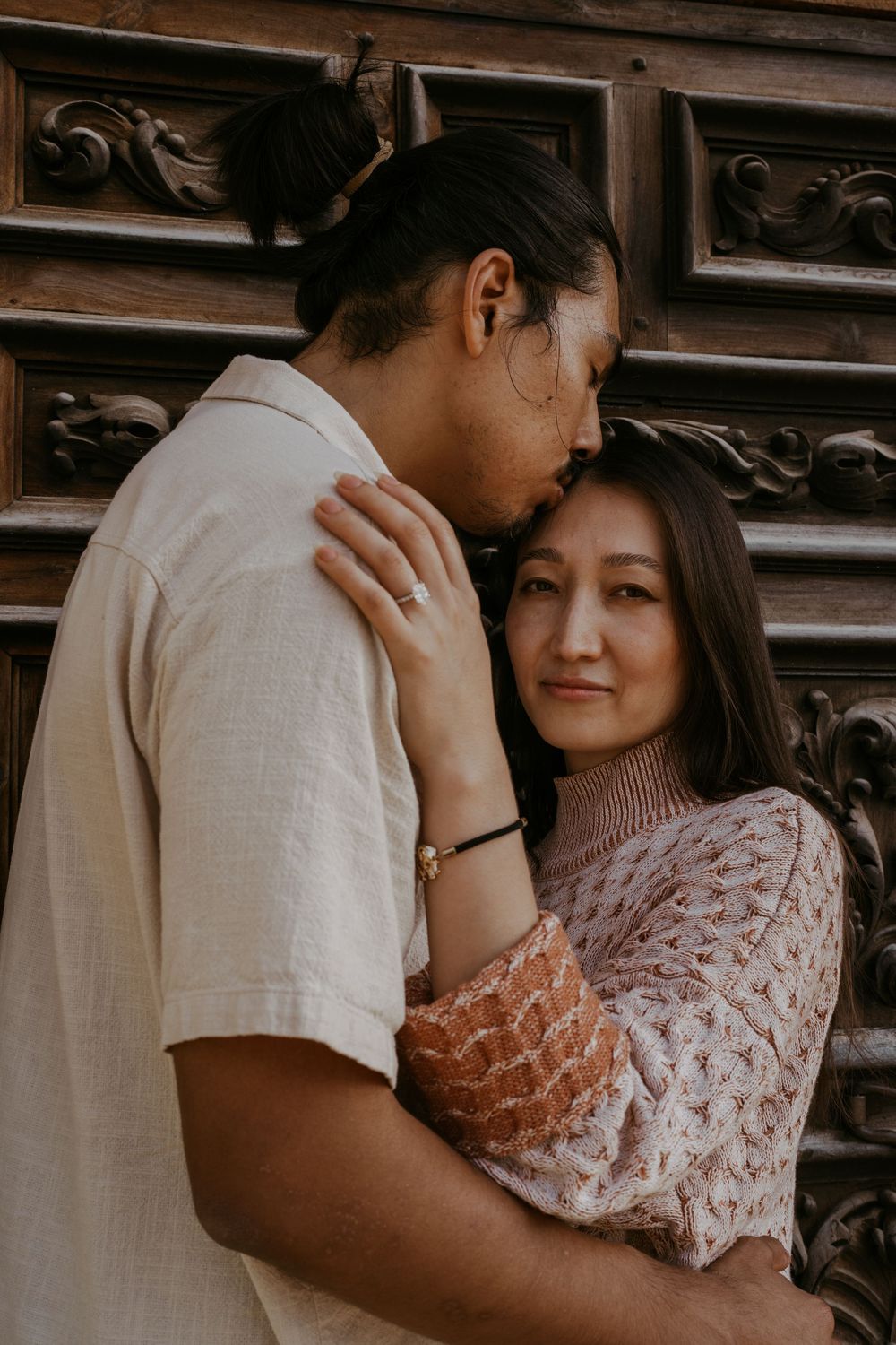 An intimate moment shared between a couple against ornate wooden paneling.