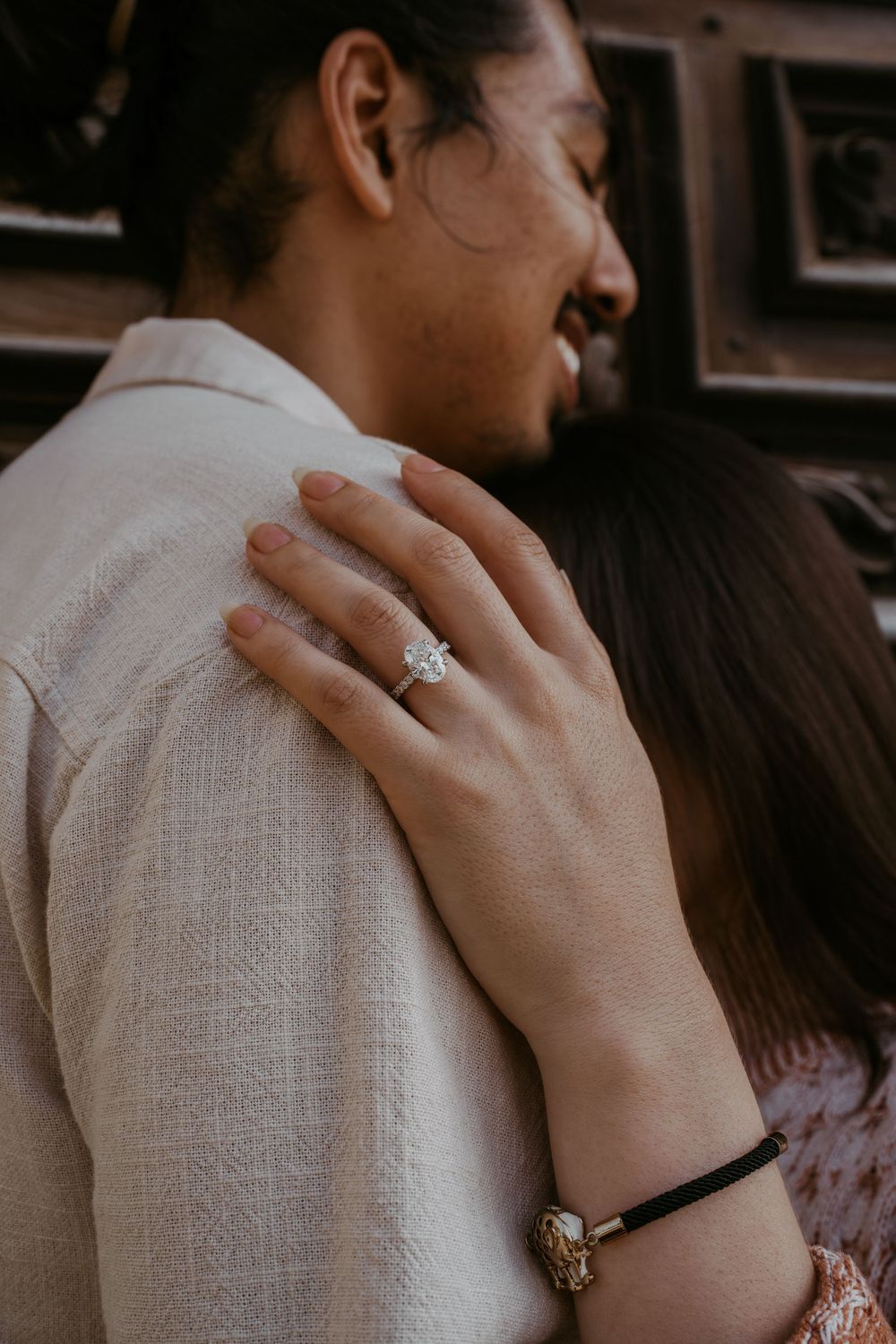 Close-up shot of hands embracing with an engagement ring visible.