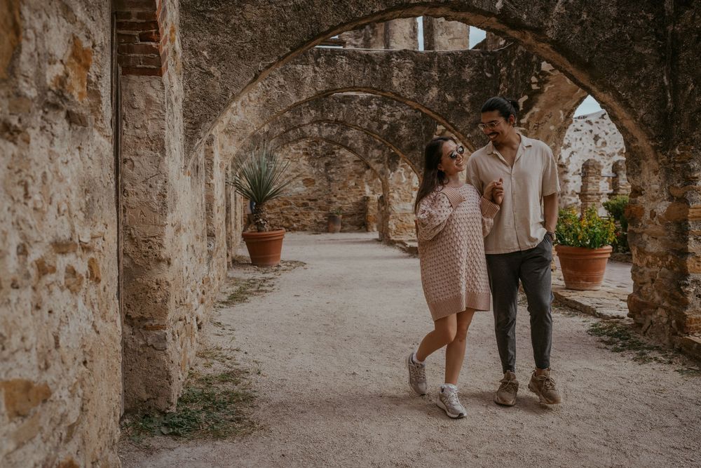 Romantic couple walking through historic stone archways.
