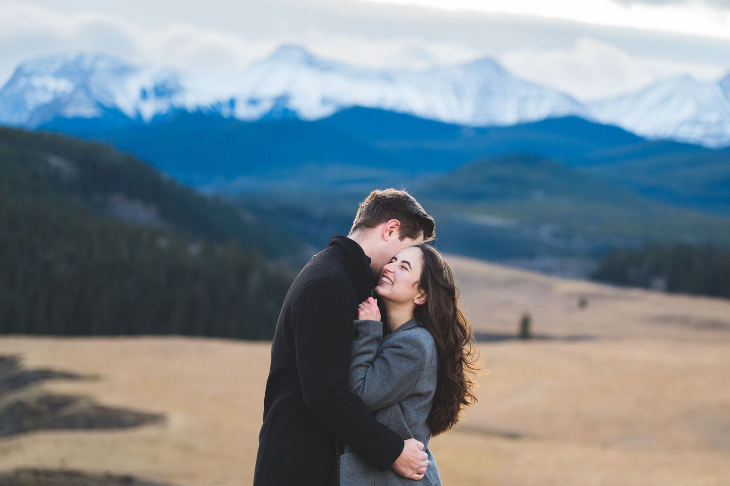 Couple sharing intimate moments in a mountain meadow during golden hour.