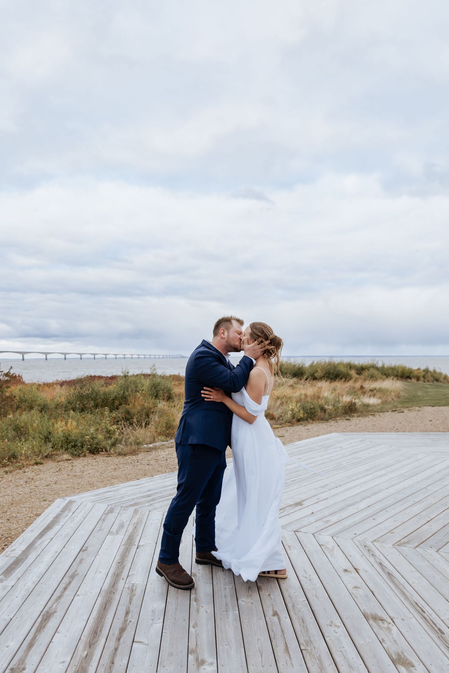 bride and groom kissing during wedding ceremony overlooking Atlantic Ocean, Confederation Bridge elopement in PEI, Summerside wedding photos