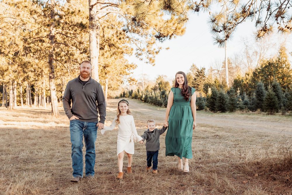 Family walking together through a sunlit forest during golden hour photography session.