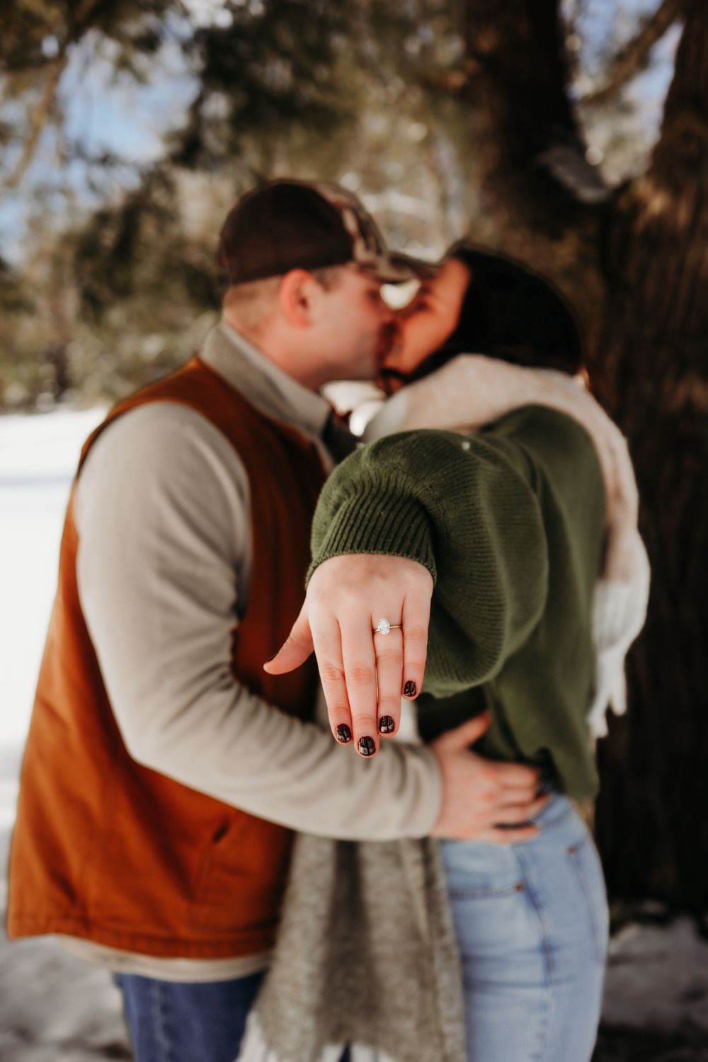 A couple embraces outdoors while showing off an engagement ring in a series of romantic announcement photos.