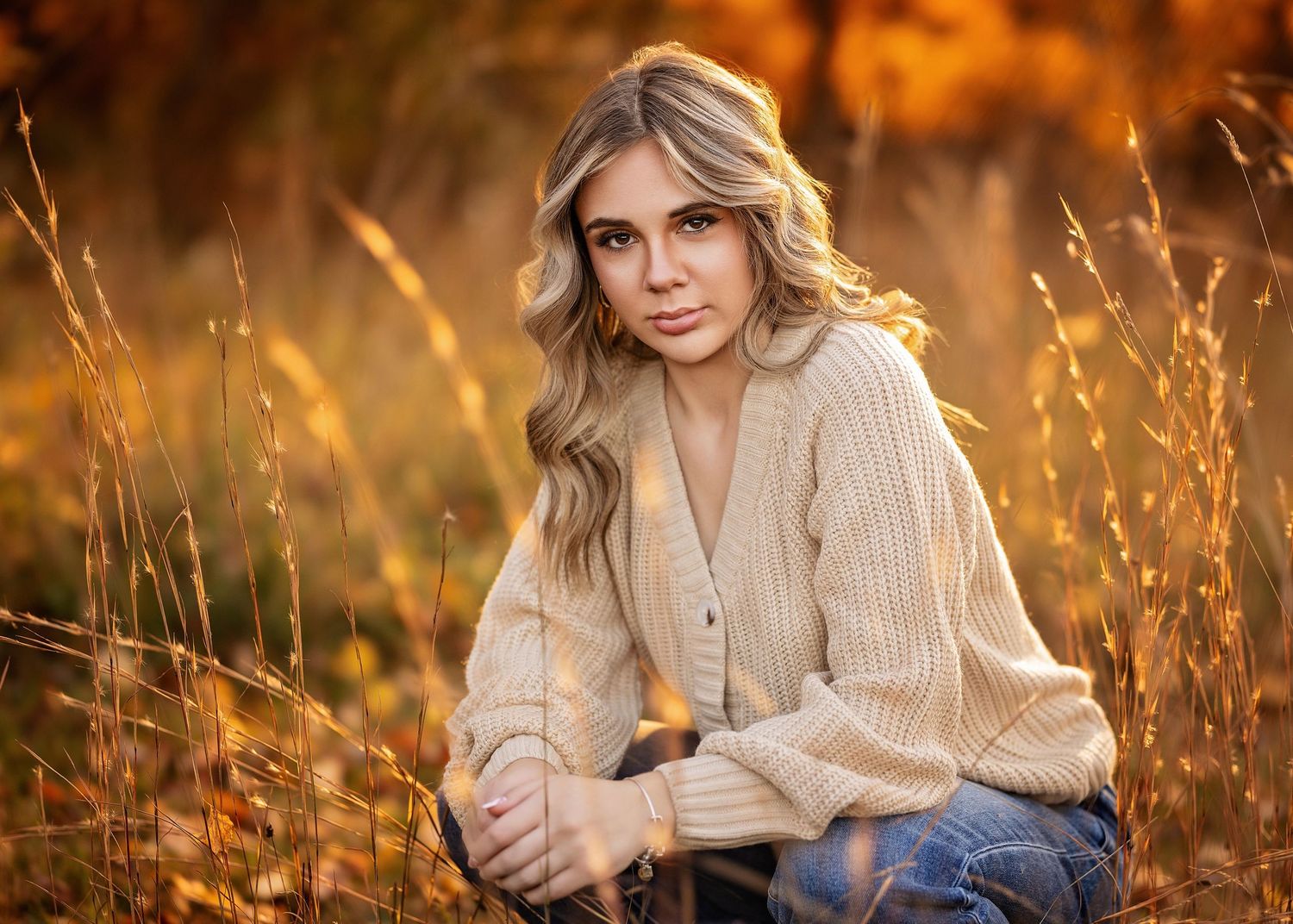 Glowing golden light illuminates a person in a white dress laying in a grassy meadow during sunset.