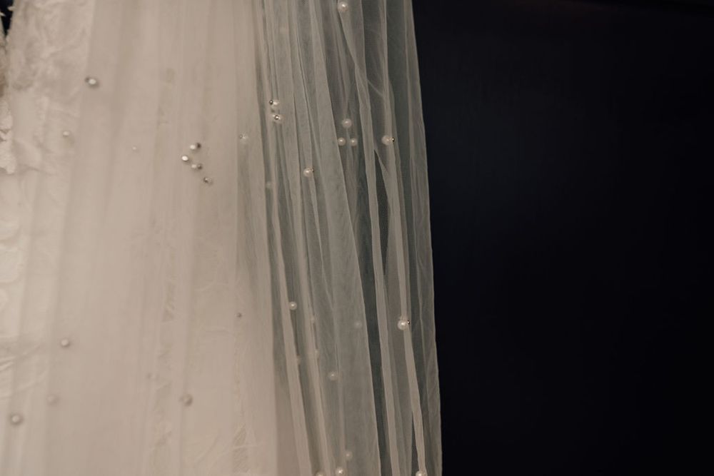 Close-up of delicate white fabric with sparkling details in dramatic lighting.