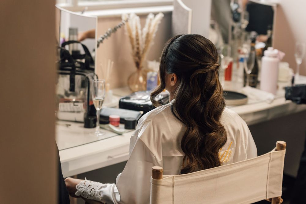 Professional makeup artist applies cosmetics in a salon setting with warm lighting.