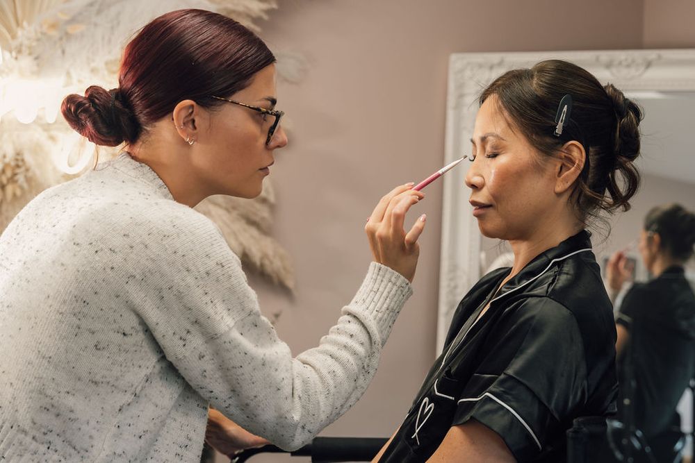 Makeup artist carefully applies cosmetics in a bridal preparation setting.