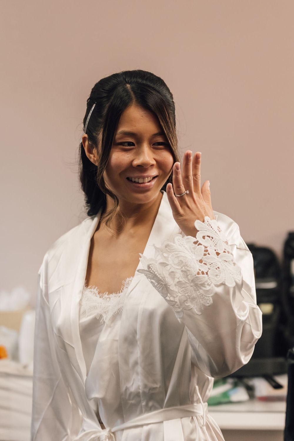 Joyful moment captured in white silk robe during bridal preparations.