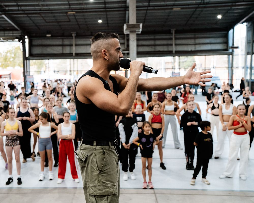 Large group of dancers practicing choreography together in a bright studio space during a dance class.