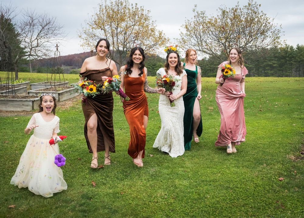 Wedding party walking through a garden with colorful bouquets and dresses.