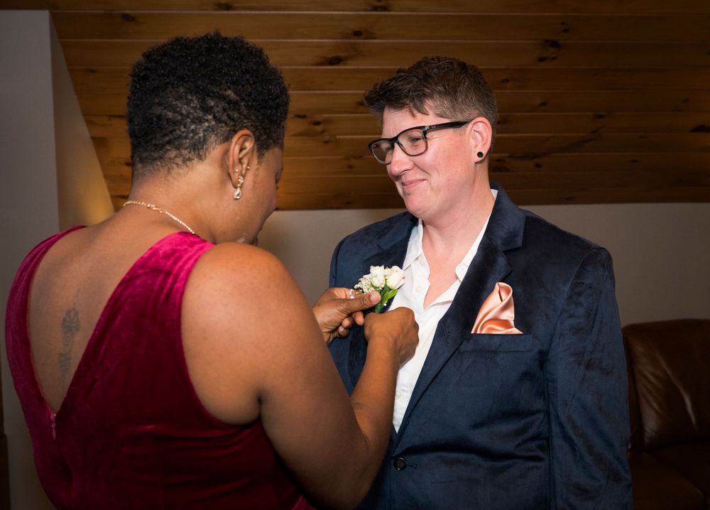 Two people share an intimate moment during a formal event in a rustic indoor setting.