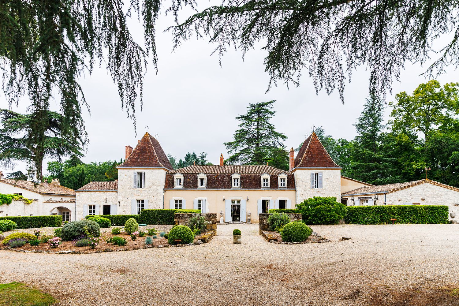 Panoramic view of a French country estate with white buildings and manicured gardens stretching across a sunny landscape.