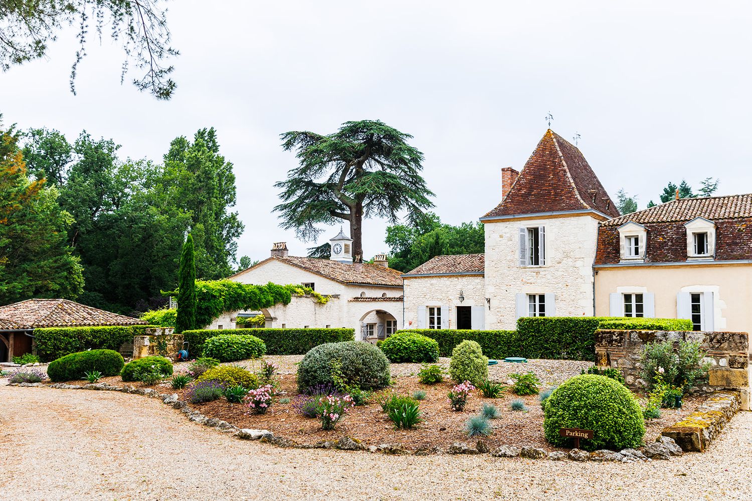 A panoramic view of traditional French countryside houses with white stone walls and rustic landscaping.