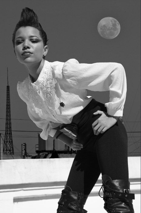 A series of black and white photos showing someone in white and black attire dancing against a moonlit sky with towers. Photo session.