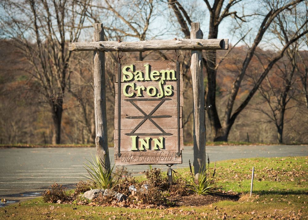 Rustic wooden sign for Salem Cross Inn featuring weathered posts and autumn foliage.