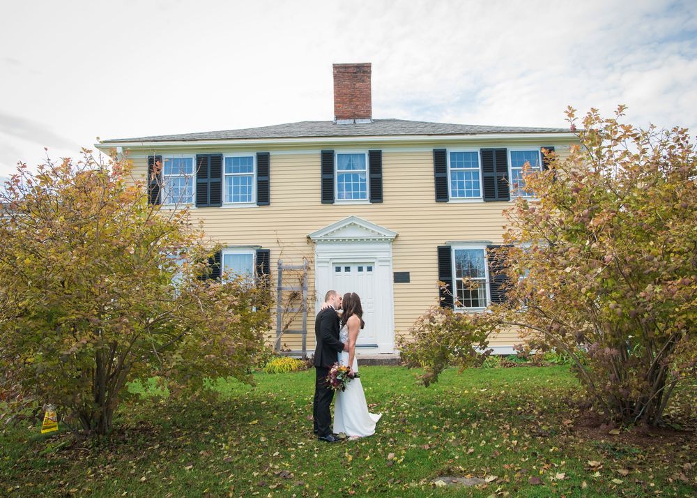 Wedding couple photographed outside a traditional New England style house in autumn.