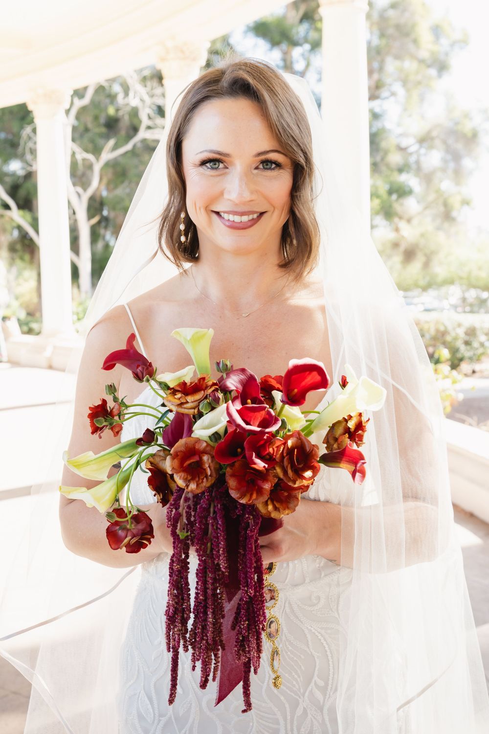 Bride holding red bouquet at Spreckels Organ Pavilion in Balboa Park