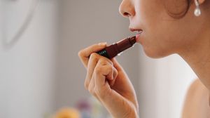 A person eating chocolate while holding a piece near their mouth.