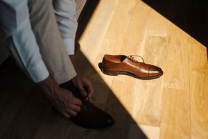 Brown leather penny loafer shoes shown in various angles on wooden flooring.