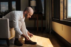 Chef carefully inspects food plating and presentation details in a dimly lit restaurant kitchen.