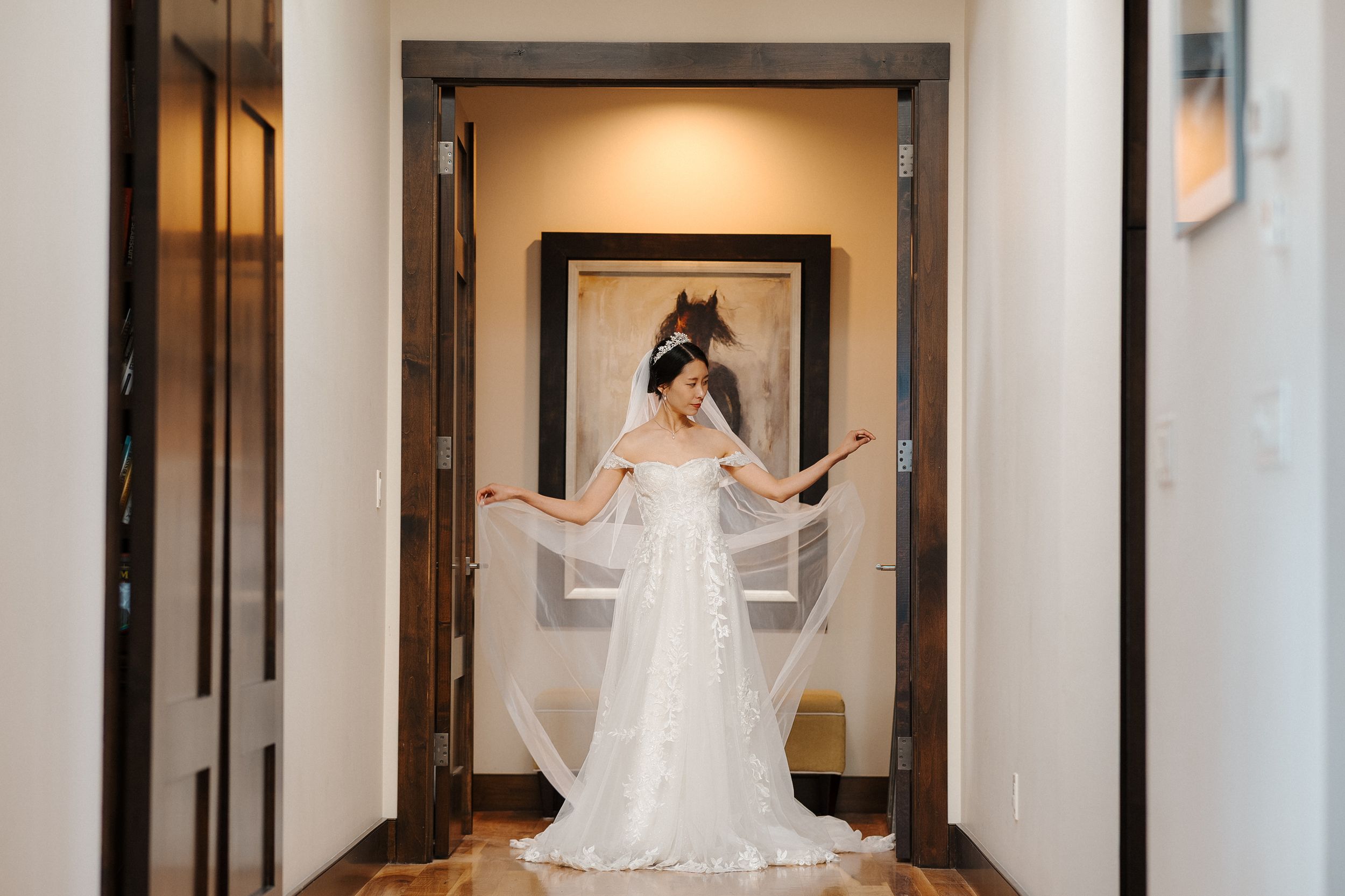 A bride in a flowing white wedding dress twirls joyfully in an elegant hotel hallway.