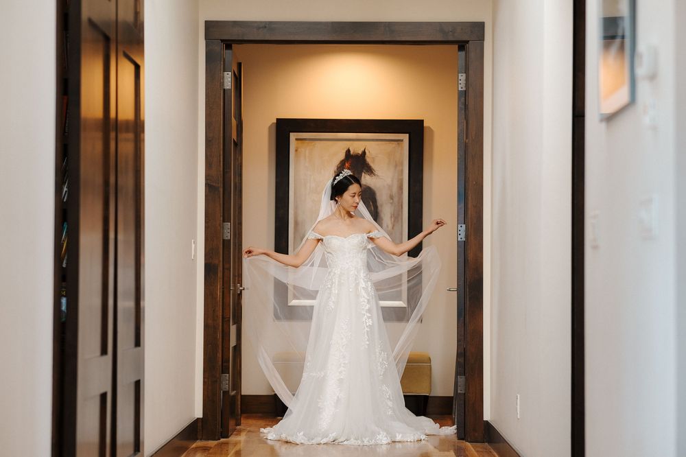 A bride in a flowing white wedding dress twirls joyfully in an elegant hotel hallway.