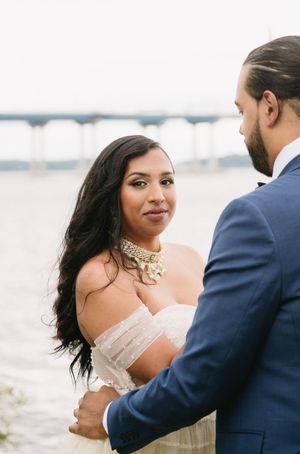 A romantic waterfront portrait of a couple in formal attire.